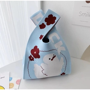 Detail of light blue knitted tote bag featuring red floral and cartoon ghost patterns