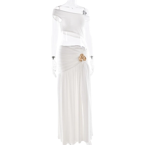 Detailed view of white two-piece set featuring a gold flower buckle and pleated skirt design