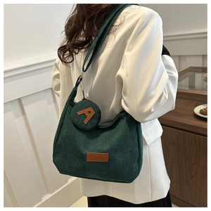 Detail of dark green corduroy tote bag with brown leather labels and round coin purse