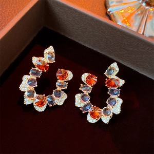 Macro shot of C-shaped drop earrings with gradient zircons in a brown jewelry box