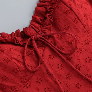 Macro shot of red eyelet embroidery cotton fabric with ruffled collar and tie detail