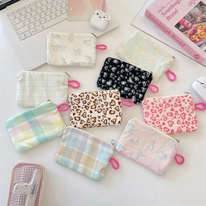 Flat lay of colorful floral canvas pouches for coins and earphones on desk