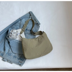 Detail of olive green nylon hobo bag with pleated texture on denim jacket background