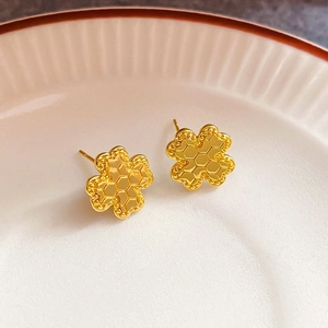 Macro detail of gold clover earrings with honeycomb pattern and beaded edges