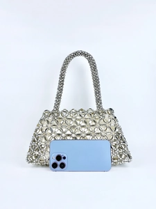Detailansicht einer silbernen Perlenhandtasche mit ovalen Metallperlen und Henkel