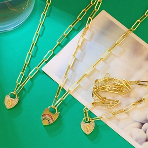 Détail du collier à grosse chaîne dorée avec pendentifs cœur sertis de diamants et arc-en-ciel
