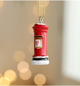 Close-up of red Christmas mailbox ornament with snow details and golden hanging chain