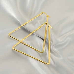 Minimalist gold triangle hoop earrings in polished stainless steel on silk fabric