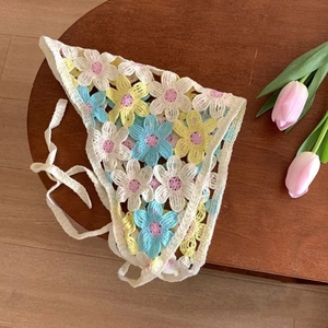 Close-up of handmade crochet triangle headscarf with colorful floral patterns on wooden table