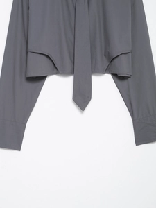 Detailed close-up of grey poplin cropped shirt featuring tie-knot hem and button cuffs