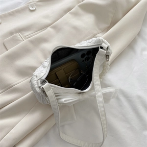 White textured shoulder bag with pearl handle and chiffon bow showing interior storage