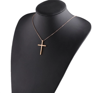 Detailed view of polished rose gold cross pendant on a black bust mannequin display