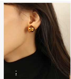 Macro shot of model wearing a large high-polish 18k gold-plated ball stud earring
