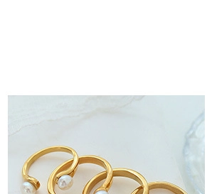 Detailed view of minimalist gold open rings with elegant white pearls on textured backdrop
