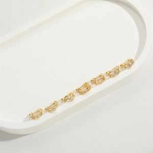 Close-up of seven gold-plated U-shaped ear cuffs with zircon accents on a tray