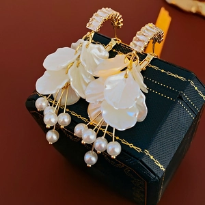 Detailed view of pearl tassel earrings with zircon petals on vintage jewelry box
