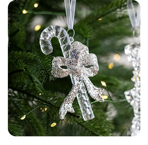 Close-up of clear acrylic candy cane ornament with silver glitter bow on Christmas tree