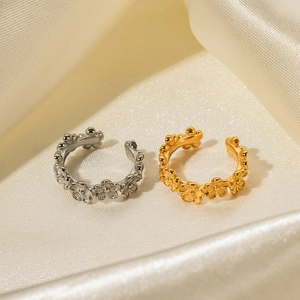 Gold and silver C-shaped stainless steel flower rings on a beige silk background