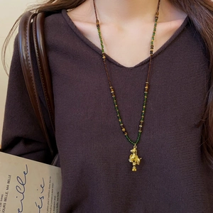 Detailed close-up of a vintage tiger eye beaded necklace with a golden horse pendant