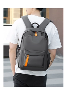 Close-up of a grey waterproof backpack with vibrant orange zippers on a person's back