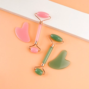 Detailed view of pink and green resin facial rollers with matching heart scraping boards