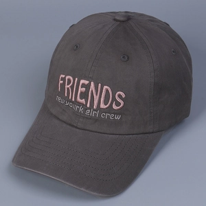 Close-up of embroidered pink Friends text on a dark gray washed cotton baseball cap