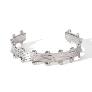 Detail of silver open cuff bracelet with brushed texture and small sphere decorations