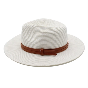 Gros plan d'un chapeau de paille blanc avec bande en cuir marron et texture tissée