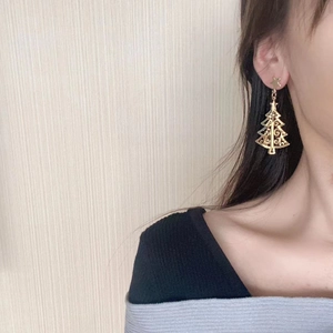 Golden Christmas tree drop earrings with star stud worn by model for festive jewelry style