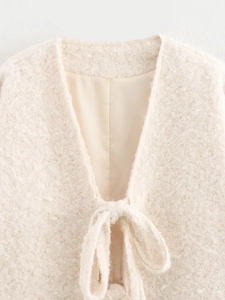 Detailed macro view of cream-colored textured bouclé knit cardigan with soft ribbon closure