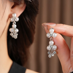 Détail de boucles d'oreilles pendantes à fleurs avec perles blanches et cristaux argentés