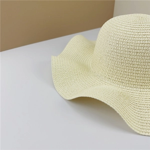 Detailed macro view of woven straw texture and wavy brim of cream sun hat