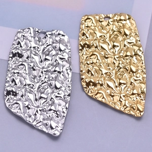 Detailed macro view of wrinkled heart pendants in gold and silver stainless steel