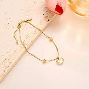 Detail of adjustable gold heart necklace with white shell inlay on a natural stone background