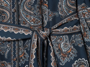 Dettaglio dell'abito paisley con bottoni rivestiti in tessuto e laccetto in vita