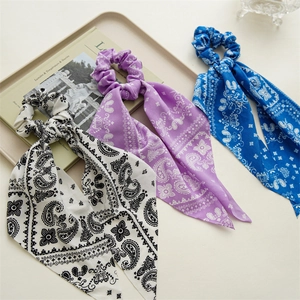 Detailed view of paisley silk scrunchies with long ribbons in black, lilac and blue