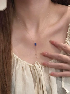 Gros plan d'un collier en chaîne dorée avec une pierre bleue carrée sur un mannequin femme