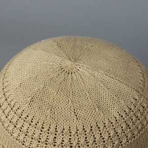 Close-up of beige knitted bucket hat showing intricate openwork crochet pattern and texture