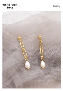Detail of white drop pearls on gold chain dangle earrings over soft grey tulle