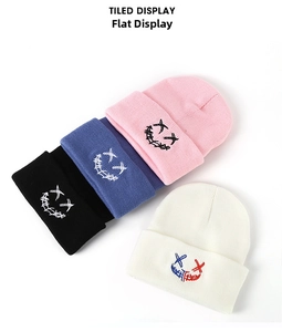 Detail of embroidered smile faces on stacked knit beanies in four distinct colors