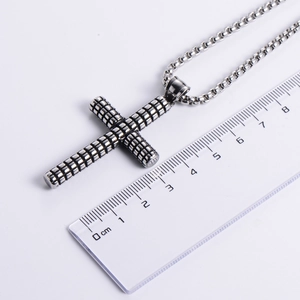 Vintage stainless steel cross pendant with grid texture showing 5.5cm size on ruler