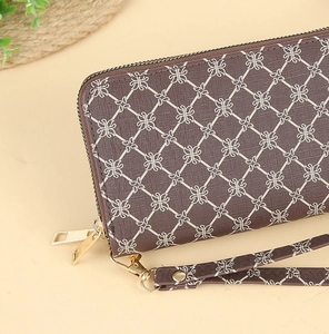 Detail of long brown wallet showing elegant diamond pattern and gold zipper with wristlet