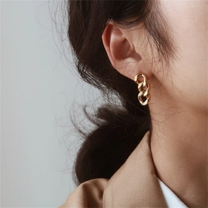 Chic gold-plated stainless steel Cuban link drop earrings worn by a model in a side profile