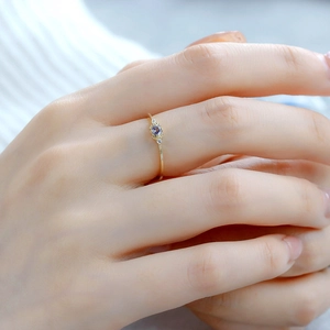 Macro shot of minimalist gold S925 ring featuring a round purple tanzanite gemstone