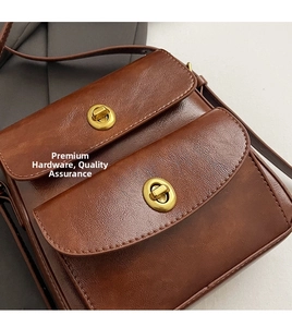 Close-up of vintage dark brown leather bag showing golden turn-lock hardware and dual pockets