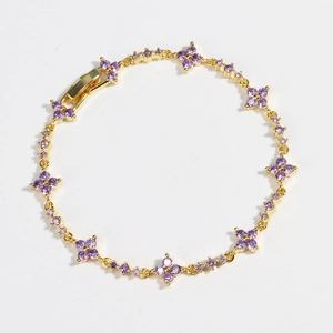 Macro view of gold flower bracelet featuring purple zircons and clover motif details