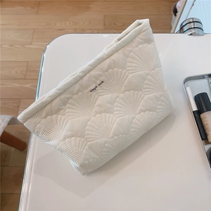 Close-up of white quilted shell-pattern makeup bag with simple wish logo label