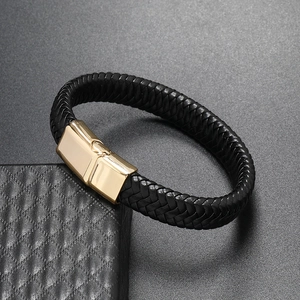 Macro detail of men's black braided leather bracelet with golden magnetic clasp