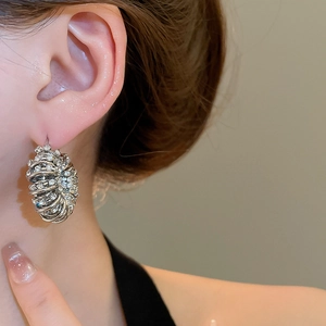 Close-up of silver multilayer spiral hoop earrings with pavé rhinestones on model