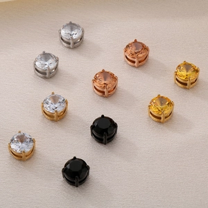 Macro detail of magnetic zircon earrings in silver, gold, and black with shiny stones